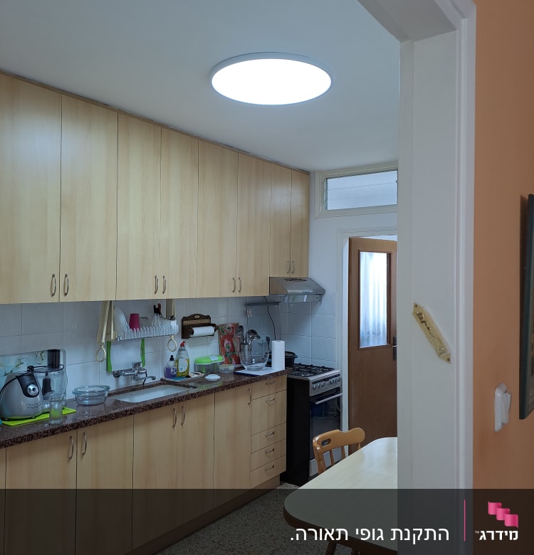 תאורה עגולה בתקרה במטבח עם ארונות עץ